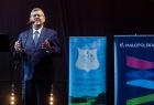Widok na stojącego na scenie marszałka Witolda Kozłowskiego. Marszałek stoi na scenie w tle za nim widać dwa rolapy- województwa małopolskiego i Kobylaniki. 