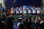 Widok na zespół regionalny w tradycyjnych ludowych strojach występujący na scenie. 