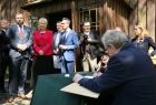 Premier Piotr Gliński składający podpis przed jednym z zabytkowych drewnianych kościołów