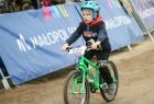 Chłopiec na zielonym rowerze na tle banneru z napisem "Małopolska"