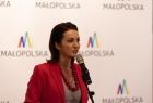 Członek zarządu Marta Malec-Lech przy mikrofonie. W tle logotyp Małopolska.