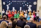 Grupa dzieci w kolorowych strojach tańczy i śpiewa