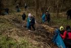 Dzieci zbierają śmieci do worków idąc przez park