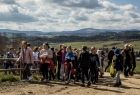 Grupa dzieci idzie szlakiem i niesie worki na śmieci, w tle niebo i góry