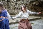 Dwie kobiety z grupy rekonstrukcyjnej w historycznych sukniach odgrywa scenkę walki na szpady.