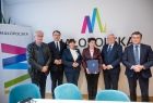 Kobieta z granatową teczką w dłoni. Obok przedstawiciele Sejmiku.