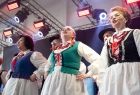 Widok na kobiety stojące w rzędzie w tradycyjnych strojach ludowych. Kobiety są w trakcie występu.