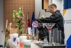 Eksperyment chemiczny, mężczyzna stoi przy stole na którym ustawiono probówki z płynami