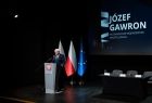 Widok na przemawiającego przy szarej mównicy wicemarszałka Józefa Gawrona. 