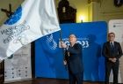 Marszałek Witold Kozłowski trzyma w rękach flagę Igrzysk Europejskich. 