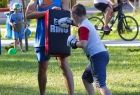chłopiec w bokserskich rękawicach uderza w matę trzymaną przez trenera