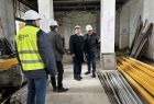 Widok na wnętrze remontowanego budynku. Pośrodku korytarza w otoczeniu mężczyzn stoi marszałek Witold Kozłowski. 