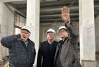 Marszałek małopolski Witold Kozłowski stoi wewnątrz remontowanego budynku. Jeden z mężczyzn stojących po lewej stronie marszałka wskazuję ręką na prace remontowe. 