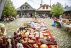 Stół zastawiony biblelotami podczas kiermaszu staroci, w tle dwa budynki Miasteczka Galicyjskiego