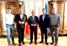 zdjęcie grupowe, marszałek z gośćmi z Myślenic na tle flag