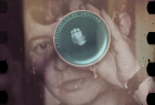 Fotografia przedstawiająca twarz kobiety trzymającej w dłoni obiektyw fotograficzny zbliżony do oka. 