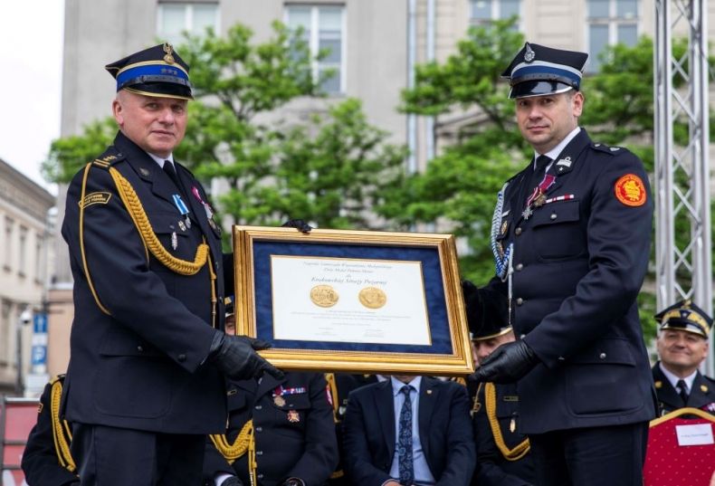 Wicemarszałek Łukasz Smółka trzyma z komendantem straży medal Polonia Minor.