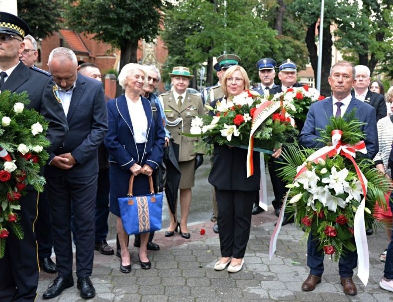 Radna województwa Marta Mordarska stoi z innymi uczestnikami wydarzenia i trzyma wieniec.