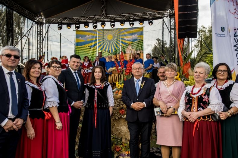 Wicemarszałek Łukasz Smółka i minister Andrzej Adamczyk stoją przed sceną z uczestnikami wydarzenia.