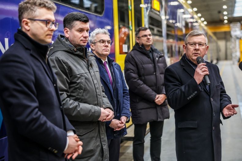 Marszałek Witold Kozłowski stoi i mówi do mikrofonu podczas wydarzenia. Obok widoczni pozostali uczestnicy wydarzenia.