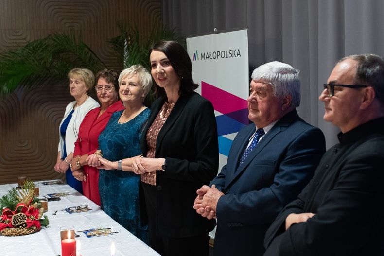 Marta Malec-Lech z zarządu województwa stoi przy stole z seniorami.