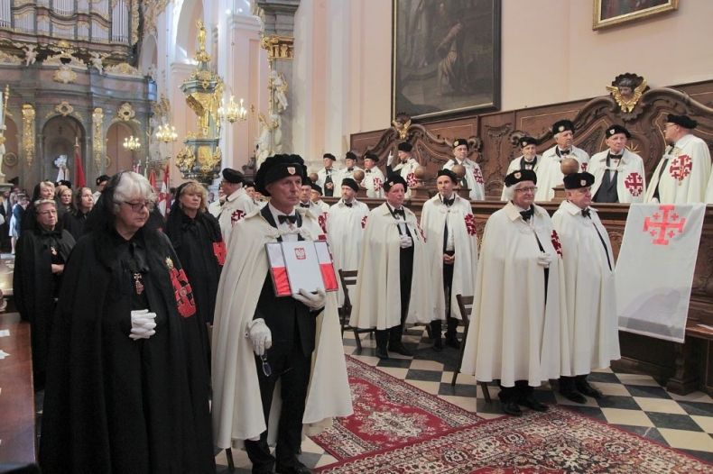 Ludzie ubrani w historyczne szaty stoją w kościele.