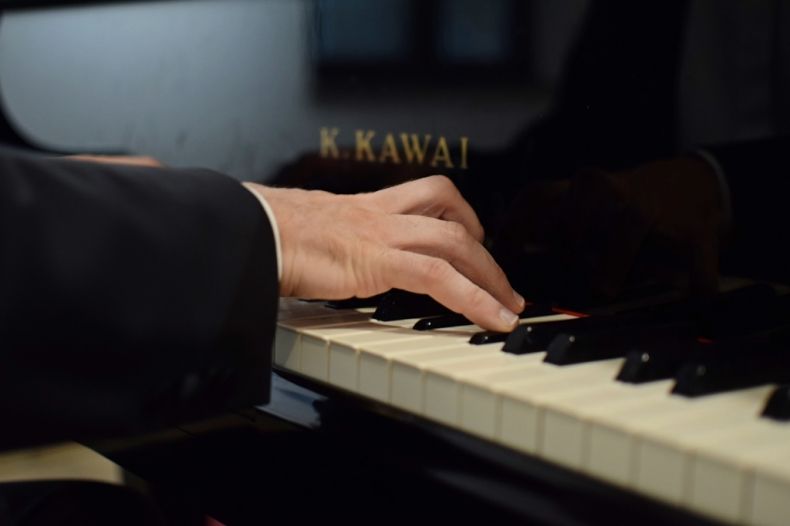 Na zdjęciu ręce pianisty na fortepianie.