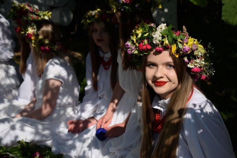 Dziewczyny w białych sukniach i wiankach na głowie ze świeżych kwiatów