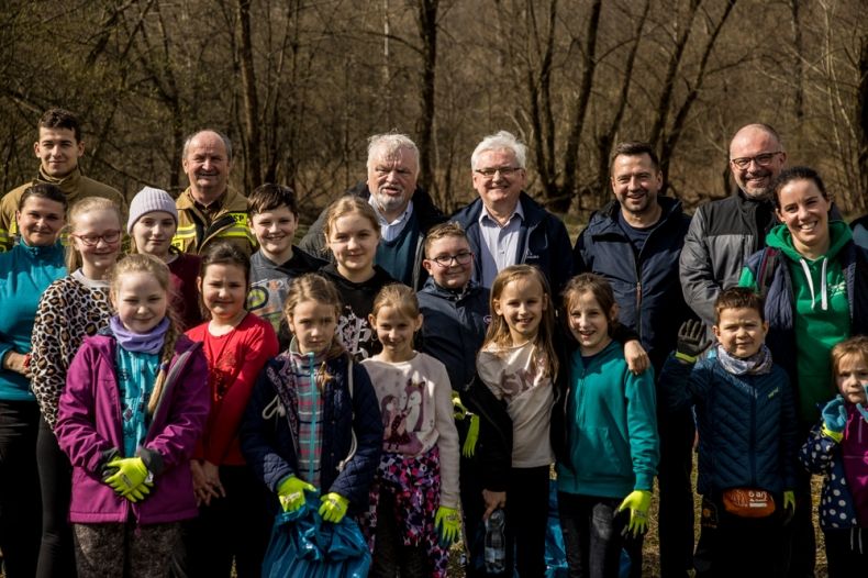 Grupa ochotników pozuje do pamiątkowego zdjęcia trzymając worki ze śmieciami