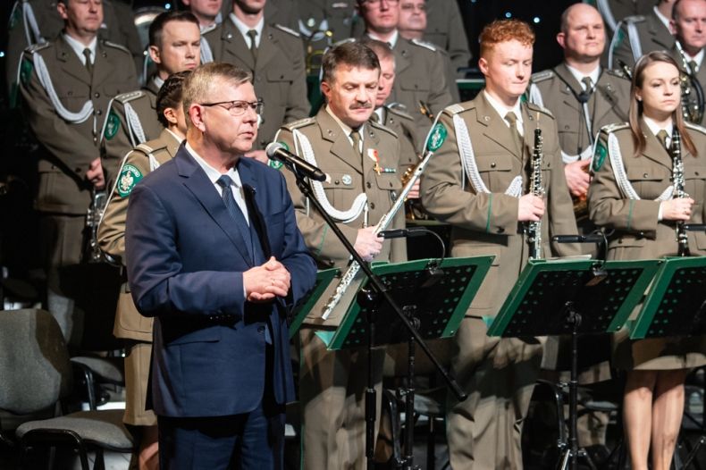 Marszałek Małopolski Witold Kozłowski w trakcie przemówienia na scenie MCK Sokół. W tle za nim widać Orkiestrę Straży Granicznej. 