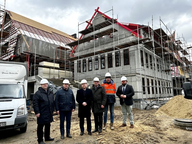 Widok na plac budowy i stojących na nim marszałka Witolda Kozłowskiego i pozostałych mężczyzn. 