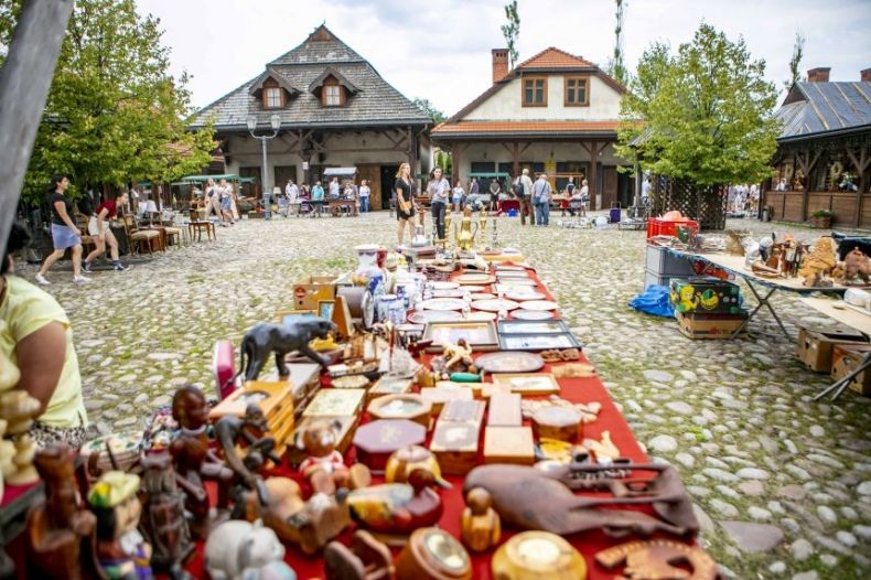 Stół zastawiony biblelotami podczas kiermaszu staroci, w tle dwa budynki Miasteczka Galicyjskiego