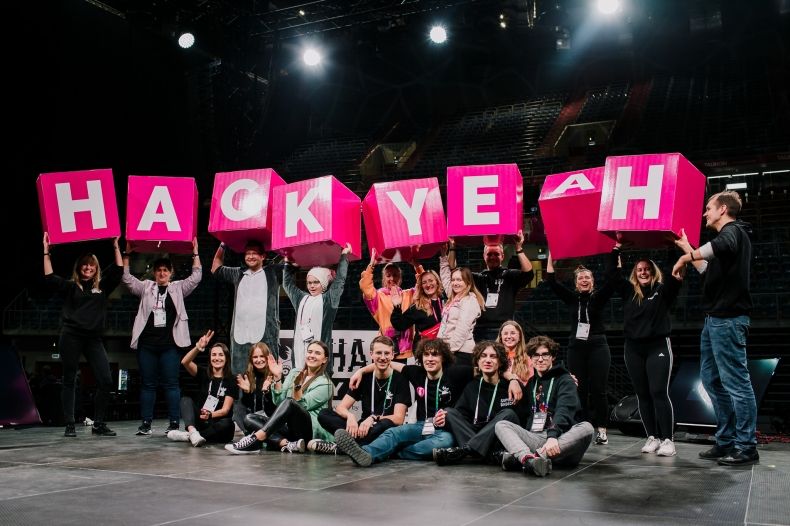 Młodzi ludzie na scenie trzymający napis HackYeah