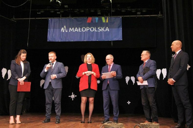 Grupa osób stoi na scenie, w tle banner z napisem Małopolska