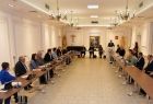 Grupa osób siedzi przy stołach konferencyjnych w dużej jasnej sali
