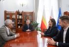 Trzy osoby przy stole w rozmowie z wicemarszałkiem Witoldem Kozłowskim. 