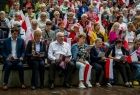 Wicemarszałek Ryszard Pagacz siedzi na widowni amfiteatru i śpiewa.