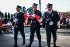 Strażacy niosą złożoną flagę Polski.