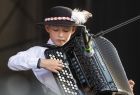 Chłopiec w stroju góralskim gra na akordeonie.