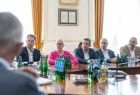 Uczestnicy spotkania siedzą przy stole i rozmawiają.