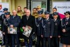 Wicemarszałek Pagacz stoi ze strażakami i trzyma dyplom.