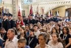 Ludzie w kościele stoją i siedzą w ławkach.