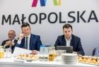 Marszałek Łukasz Smółka siedzi z mężczyznami przy stole.