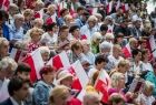 Tarnowianie śpiewają trzymając biało-czerwone flagi.