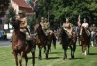 Żołnierze jadą na koniach po trawie.