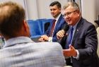 Wicemarszałek Witold Kozłowski siedzi przy stole i trzyma mikrofon.