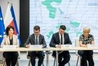 Uczestnicy wydarzenia siedzą przy stole i podpisują umowę.