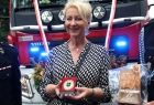 Iwona Gibas z zarządu województwa prezentująca pamiątkową strażacką odznakę