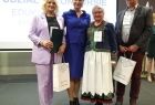 Iwona Gibas z zarządu województwa stoi na scenie z laureatami.
