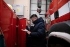 Wicemarszałek Łukasz Smółka ogląda strażackie rękawice w garażu OSP.